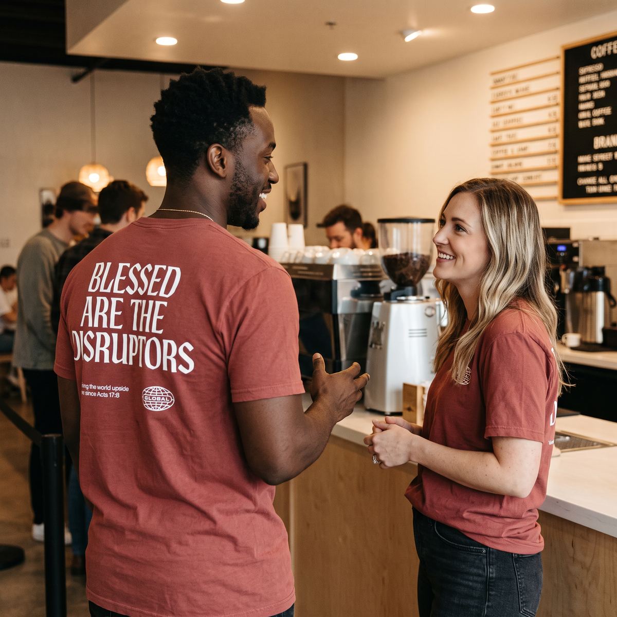 Two hosts wearing Founder's Table shirts, talking in a coffee shop